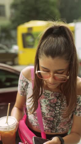 teenage girl talking on the phone and drinking coffee outdoors