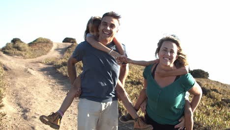 padres felices cargando a sus hijos y caminando