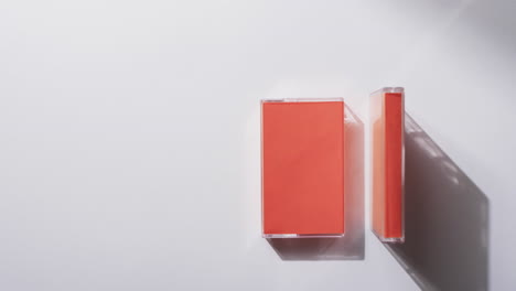 video of two retro orange cassette tape boxes with copy space on grey background