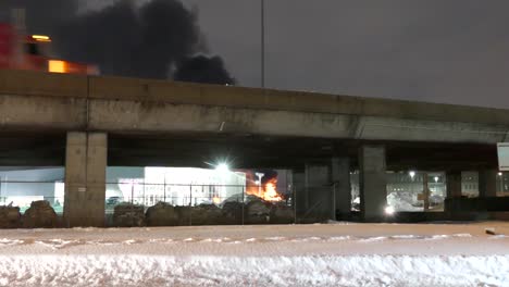 fire truck crosses bridge as thick black smoke rises from industrial blaze