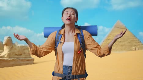 asian female hiker with mountaineering backpack smiling and spreading arms enjoy looking the view around while traveling in pyramid of giza