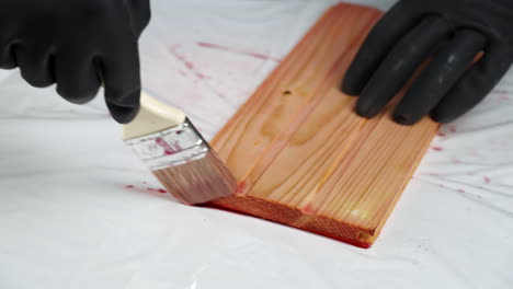 applying red stain to a wooden plank