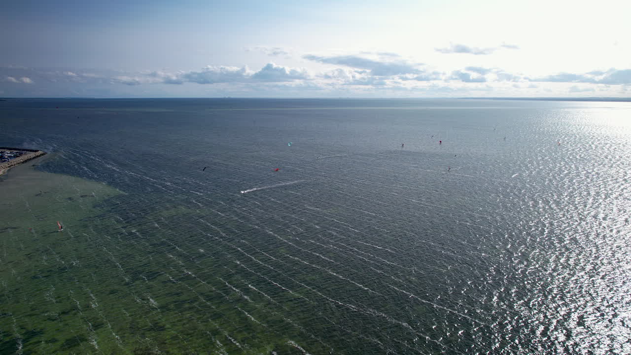 폴란드 의 황금 해 가 지는 시간 에 발트 해 에 있는 카이트 서퍼 들 의 그룹 을 보여 주는 공중 사진
