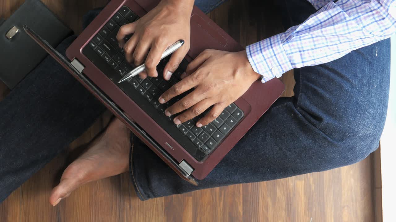 Person typing on laptop while sitting on floor