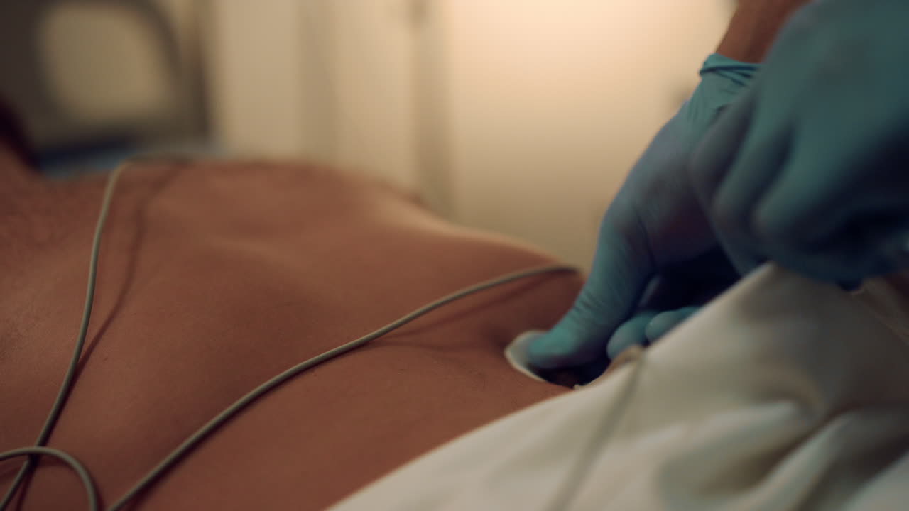 Doctor put ECG wires on patient chest close up. Hospital cardiac treatment.