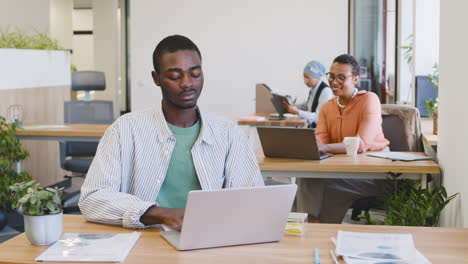 joven trabajador que trabaja con una laptop sentada en su escritorio 1