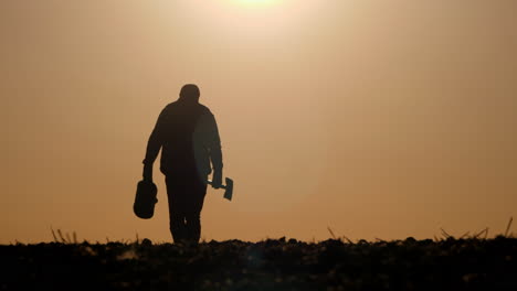 silhouette of a farmer working in a field at sunset