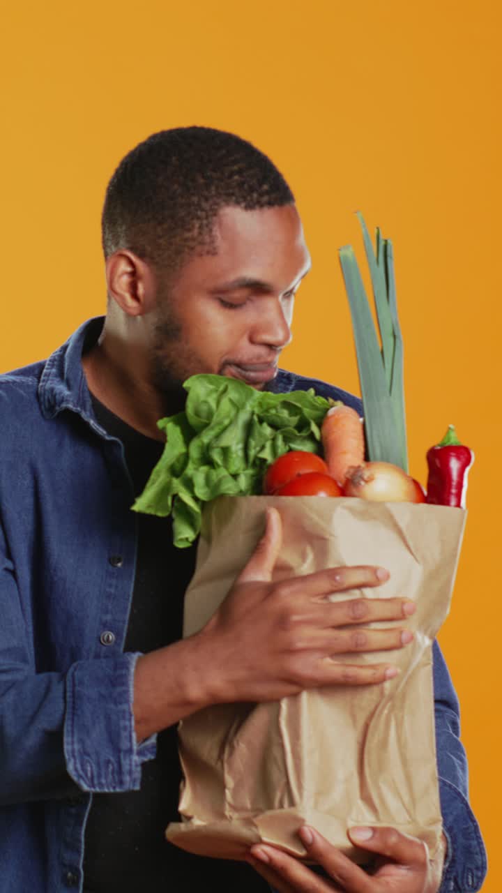 Hombre feliz oliendo verduras frescas en una bolsa de papel