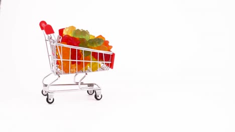 el carrito de compras con caramelos de goma dulces en forma de oso se mueve hacia adelante. aislado en el fondo blanco. primer plano. macro.