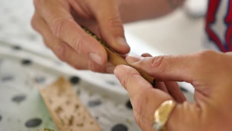 Someone-rolling-a-cannabis-joint-on-a-picnic-table