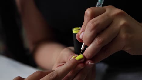 anonymous ethnic doing manicure to client and applying nail polish