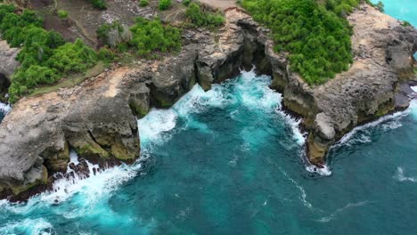 aerial of dangerous tropical coastline with turquoise waves crashing on sharp rocks