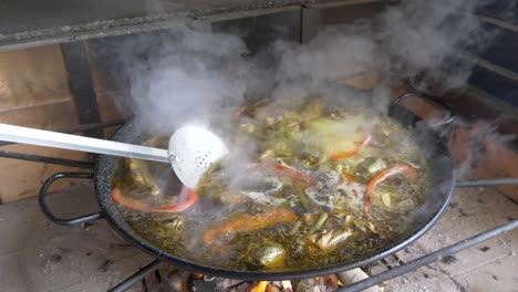 traditional spanish paella cooking on a fire with vegetables