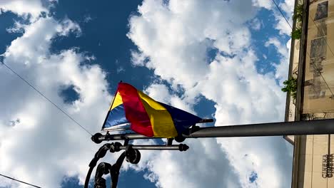 vertical romanian flag on city street lamp blown by wind, low angle