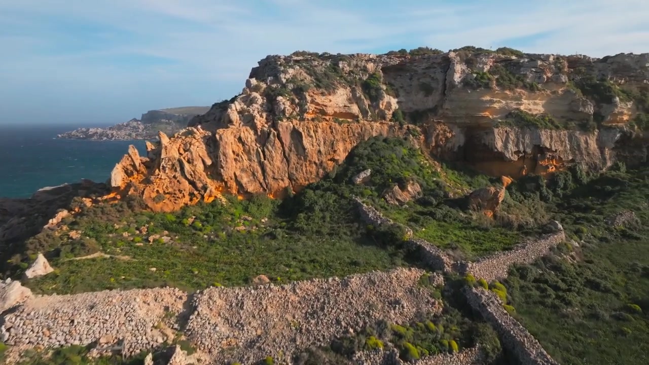 Vista aerea con drone di un lussureggiante paesaggio mediterraneo verde con rocce sulla costa a Gozo, Malta.