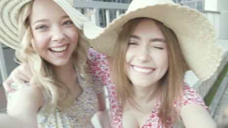 two happy young women taking a selfie on a balcony