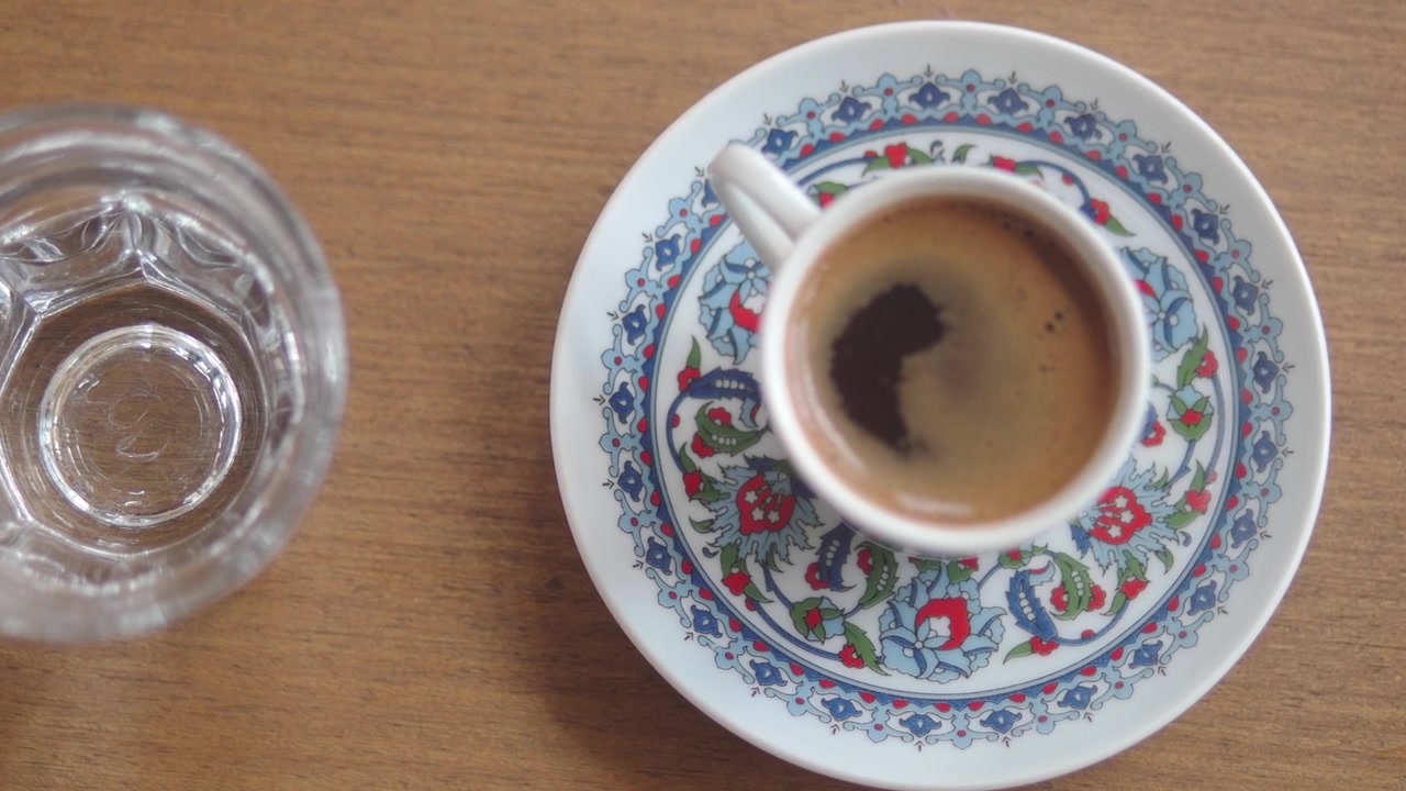 Tazza di caffè turco tradizionale con piattino decorativo e bicchiere su tavolo di legno