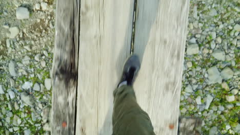 the feet of a man are walking along a narrow wooden bridge over a mountain river danger and adventur