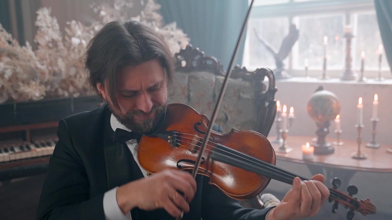 Uomo barbuto in abito che suona il violino in una stanza elegante