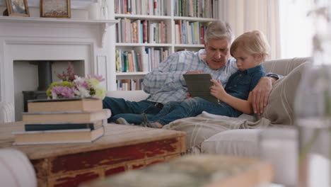 grandfather showing little boy how to use tablet computer teaching curious grandson modern technology intelligent child learning mobile device sitting with grandpa on sofa 4k