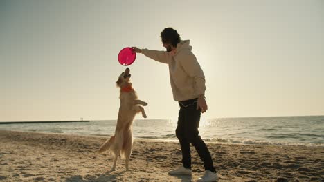 And-a-young-guy,-along-with-his-big-light-colored-dog,-are-playing-on-the-beach-in-the-morning