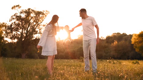 Mama-Und-Papa-Schütteln-Das-Kind,-Das-Auf-Seinen-Händen-Spielt.-Der-Junge-Spielt-Glücklich-Mit-Seinen-Eltern-Im-Sommer-Bei-Sonnenuntergang-Auf-Der-Straße.