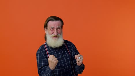 elderly bearded man celebrate success win scream rejoices doing winner hands gesture say yes