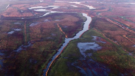 scenic river delta through misty reddish reed and flooded farmlands