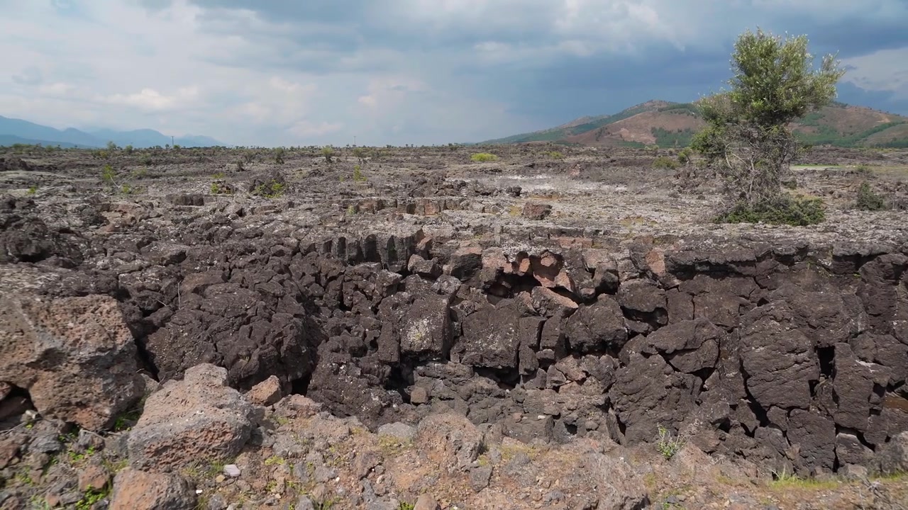 Paesaggio vulcanico con campo di lava solidificata e montagne in lontananza