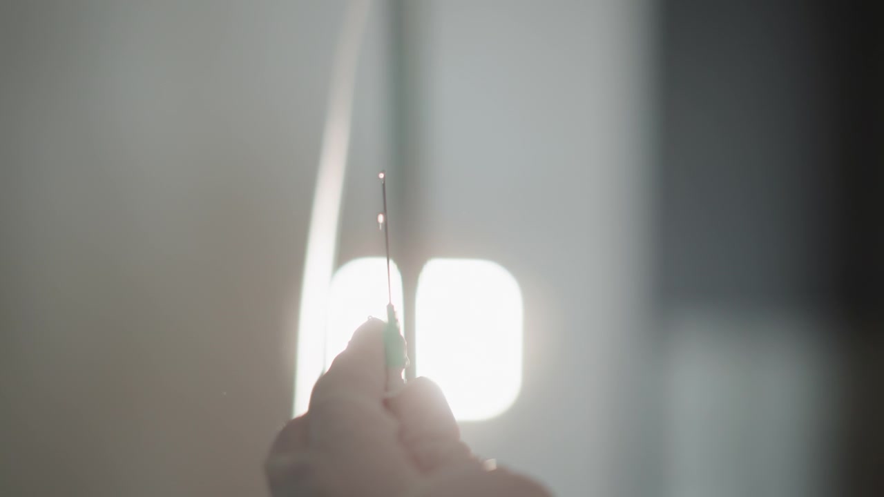 Steril teknik sikrer sikker forbindelse. Hænder justerer forsigtigt nålen med intravenøs slange under proceduren. Sundhedspersonale opretholder et fast greb for sikker infusionsforbindelse under operationen.
