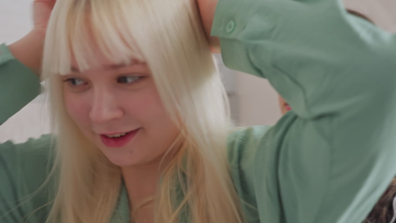 Two women in casual wear engage in heated argument over bread slice in cozy living room setting, one sits on blue sofa expressing frustration, while other stands holding bread with defensive gesture
