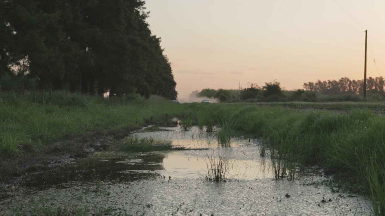 carretera de campo con zanja y charcos de agua que se forman en el lado de la carretera del vehículo