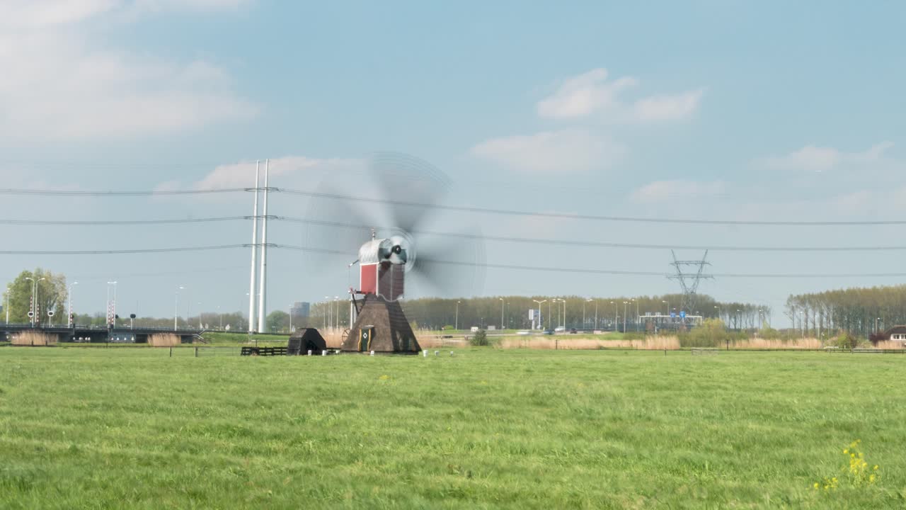 Time lapse di una struttura di mulino a vento in funzione posizionata nella prateria, vicino a un'autostrada pubblica durante il giorno.