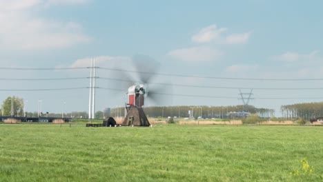 lapso de tiempo de una estructura de molino de viento en funcionamiento estacionada en la pradera, cerca de una carretera pública durante el día