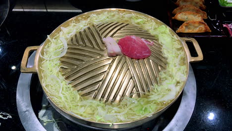 cocina japonesa jingisukan es un estilo de cocina japonesa que utiliza una sartén de metal en forma de cúpula para cocinar alimentos similares a la barbacoa, en los que los alimentos en brochetas se asan lentamente sobre un plato caliente