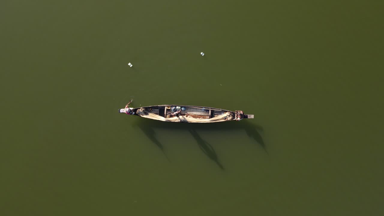 호수에 있는 작은 목선의 하향식 공중 촬영과 전통적인 방식으로 그물로 물고기를 잡는 어부