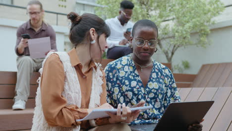 female colleagues having discussion at outdoor coworking space