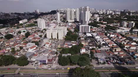 Drone-flies-over-a-residencial-area,-passes-by-a-road-and-continues-showing-houses-and-some-buildings