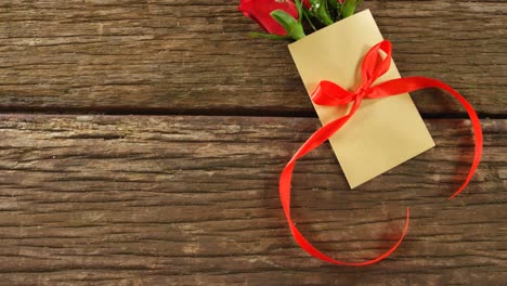 bouquet of red roses on envelope with red ribbon on wooden surface 4k