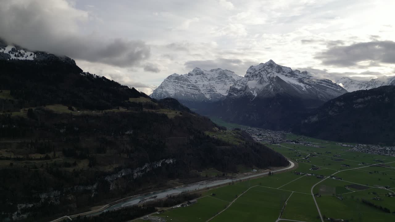 impresionantes montañas suizas con rayos de luz épicos que cruzan entre las nubes sobre los campos agrícolas