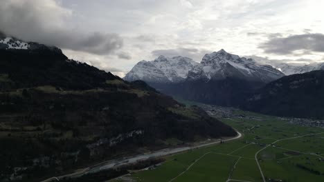 Stunning-swiss-mountains-with-epic-light-rays-crossing-between-clouds-above-farm-fields