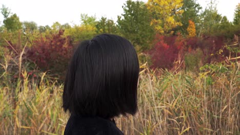 Sideways-tracking-shot-of-Japanese-girl-walking-through-autumn-park
