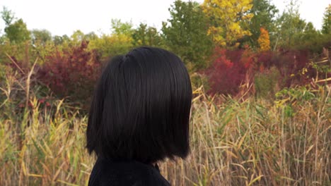 sideways tracking shot of japanese girl walking through autumn park