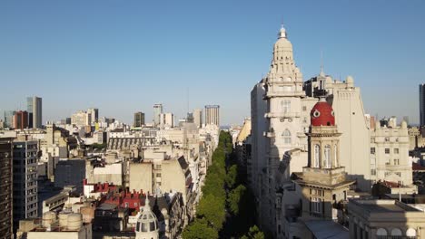 Aerial-dolly-in-of-tree-lined-May-Avenue-and-Barolo-Palace-tower-at-sunset-in-Monserrat-neighborhood,-Buenos-Aires