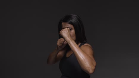 studio portrait of mature woman wearing gym fitness clothing exercising sparring at camera 1