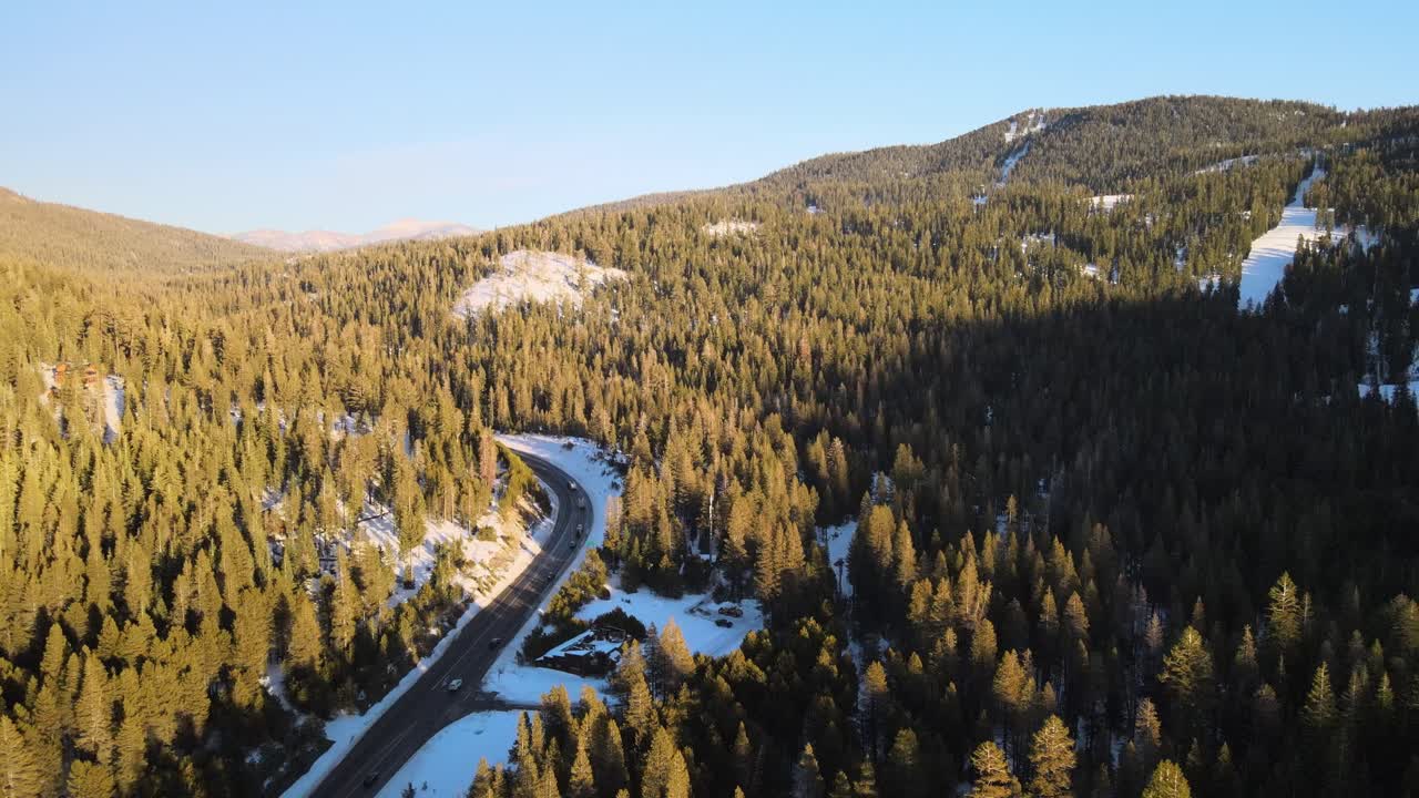 carretera asfaltada a través de un bosque de pinos en las soleadas montañas de tahoe con nieve en el suelo