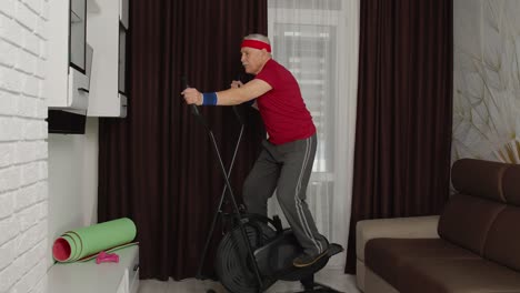 senior man in sportswear using orbitrek in living room doing sport training cardio exercises at home