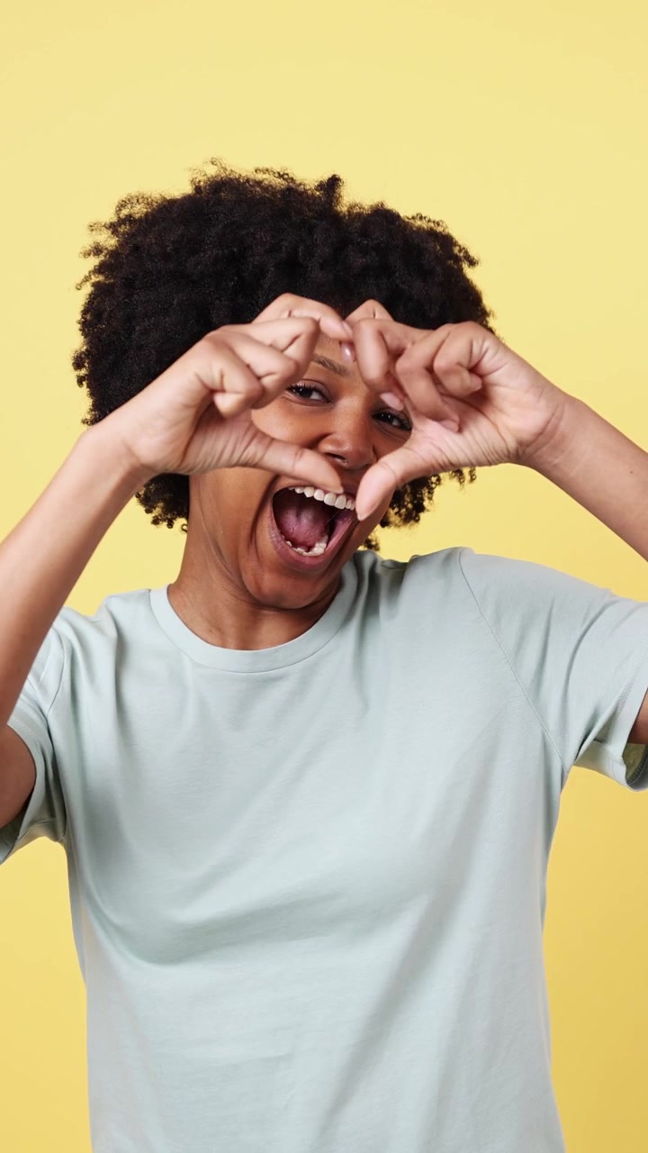 Donna afroamericana felice che fa il gesto del cuore e sorride