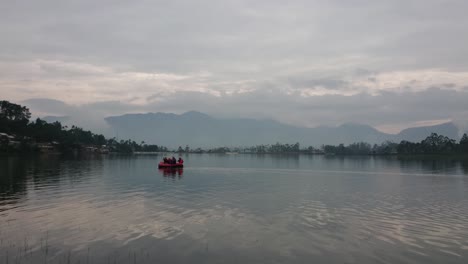 the crew is equipped on a inflatable rafting rubber boat on lake water surface at morning with beautiful view of nature around the lake