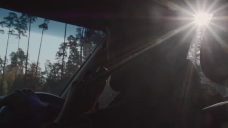 man driving a car through the forest on a sunny day